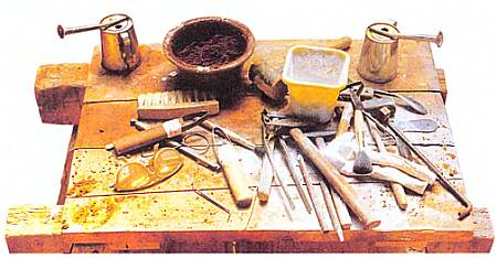 Рабочий стол скульптора, на котором лежат необходимые ему инструменты — молотки и разнообразные резцы.